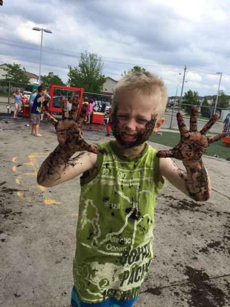 boy showing his muddy hands on mud day